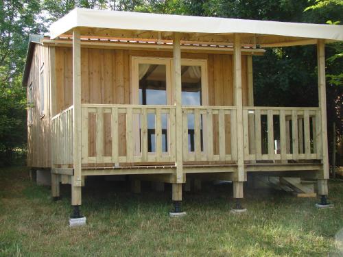 Cabaña de madera con techo sobre la hierba en CAMPING LES GRAVES - Cabane TITHOME en Saint-Pierre-Lafeuille