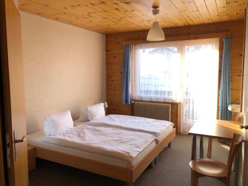 Schlafzimmer mit einem Bett, einem Schreibtisch und einem Fenster in der Unterkunft Hotel Gebidem in Visperterminen