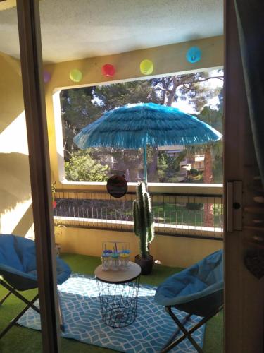 a patio with a table and a blue umbrella at Studio Paradise entre mer et pins in Saint-Raphaël