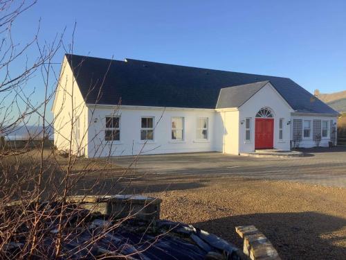 a white house with a red door at Puffin Lodge Accomodation in Killybegs