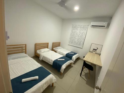 a room with three beds and a table in it at Desaru Happy Guest House D in Desaru