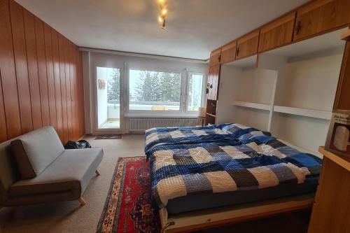 um quarto com uma cama, uma cadeira e uma janela em Apartmenthaus Gauenpark - CharmingStay em Flumserberg