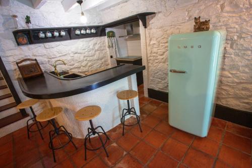 a kitchen with a refrigerator and a counter with stools at Madeira Black Sand House by Stay Madeira Island in Seixal