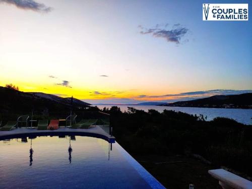 een zwembad met zonsondergang op de achtergrond bij Villa Vila in Novalja