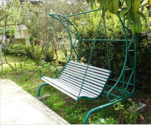 un banc à bascule vert dans un parc dans l'établissement Дом под ключ, à Gagra