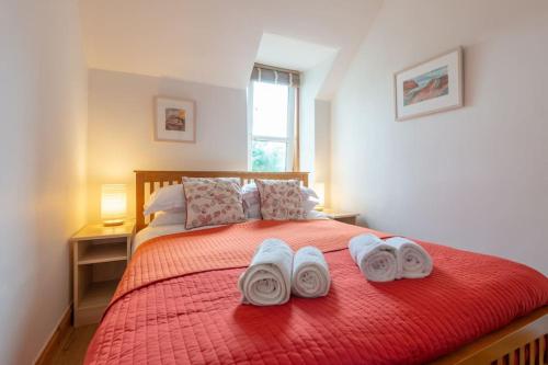 ein Schlafzimmer mit einem roten Bett mit Handtüchern darauf in der Unterkunft The 'Fairy Hill' Apartment in Inverness