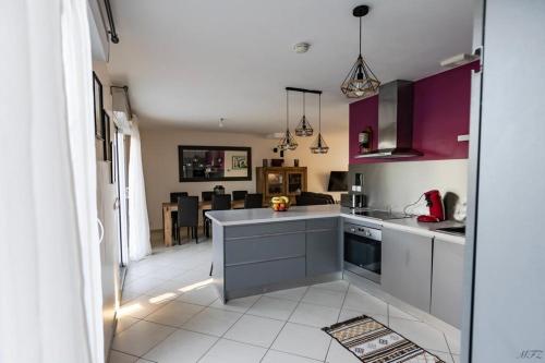 une cuisine avec des placards violets et un salon dans l'établissement Maison au calme, proche Paris et Disney, à Mitry-Mory