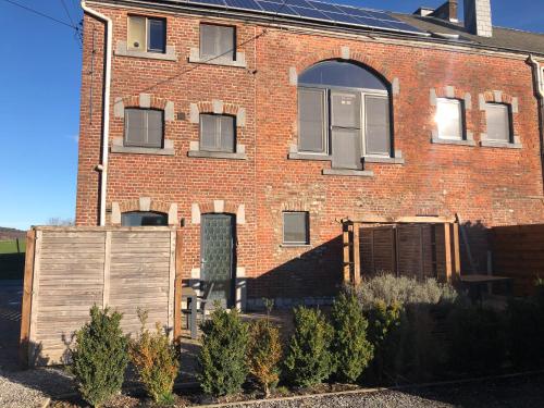 a red brick building with a wooden fence in front of it at Les Gîtes "Le Petit Val" in Durbuy