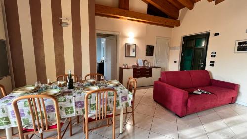 een woonkamer met een tafel en een rode bank bij Casa Meda Tabachere Appartamento Sirmione Desenzano del Garda in Pozzolengo