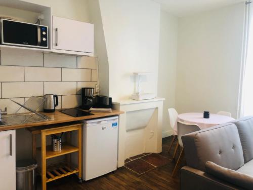 a small kitchen with a table and a microwave at Appartement T2 proche gare - DABNB in Limoges