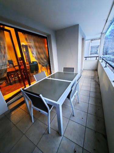 une table et des chaises dans une pièce avec une grande fenêtre dans l'établissement Entre Lac d'Annecy et montagnes, golf et parapente à pieds, à Talloires