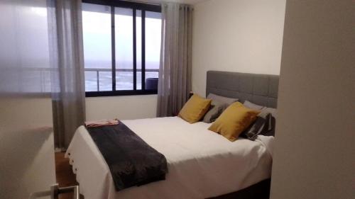 Modern apartment first line beach Montevideo UY في مونتيفيديو: غرفة نوم بسرير ومخدات صفراء ونافذة