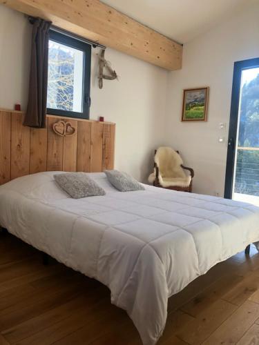 ein Schlafzimmer mit einem großen Bett und einem Stuhl in der Unterkunft Villa Marcassin in Boulc