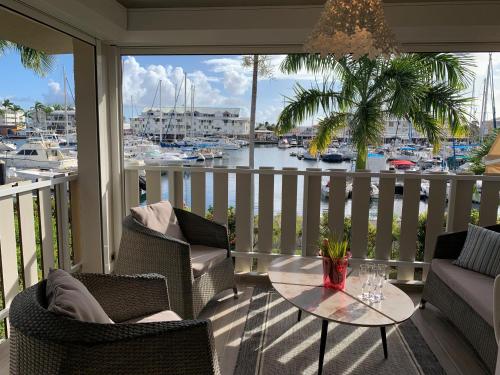 een balkon met een tafel en stoelen en een jachthaven bij Marina MANZANA, Appartement neuf, vue mer exceptionnelle - LUXE in Saint-François