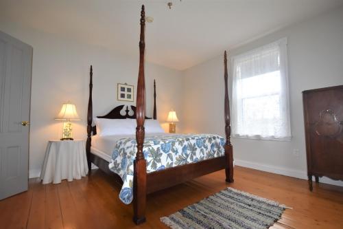 a bedroom with a bed and a table with two lamps at Hillcrest Hall Country Inn in Port Hood