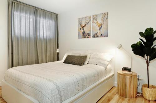 a white bedroom with a white bed and a window at 100 Chemin des Ruisselets in Stoneham