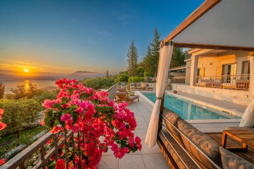 a house with a balcony with a pool and flowers at Luxury villa above emblisi beach , with heated pool ! in Fiskardho