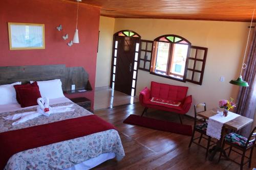 a bedroom with a bed and a red chair at Pousada Aconchego da Valdirene in Lavras Novas