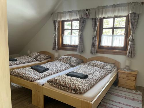 3 camas en una habitación con ventanas en Apartmán Javorník a Javorníček en Velké Karlovice