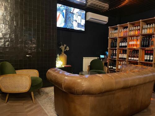 a bar with a brown leather couch and chairs at Ostan Hôtel Boutique in Roquebillière