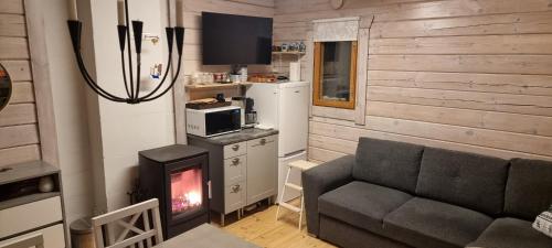 a living room with a couch and a stove at Mukava pieni 2-4h mökki min 2 vrk Saimaan rannalla, poreallas, puusauna, Wi-Fi, Smart TV, parivuode ja vuodesohva in Savonlinna