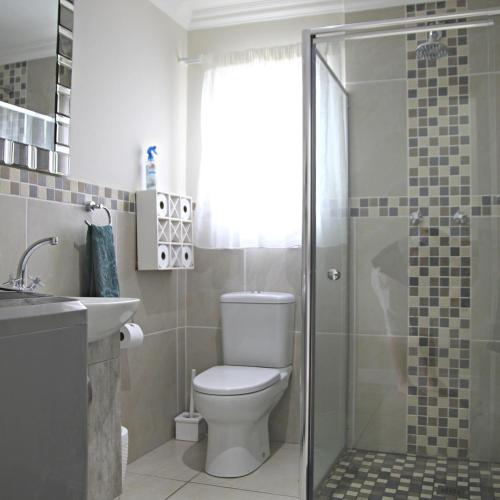 a bathroom with a toilet and a glass shower at Allalapstix in Reebok