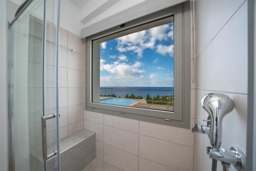 a bathroom with a window with a view of the ocean at Baklava Villa in Fiskardho