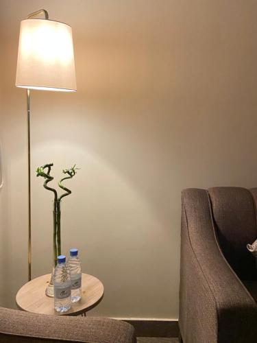 einen Tisch mit einer Lampe und einer Blumenvase in der Unterkunft الأراضي السبع in Yanbu
