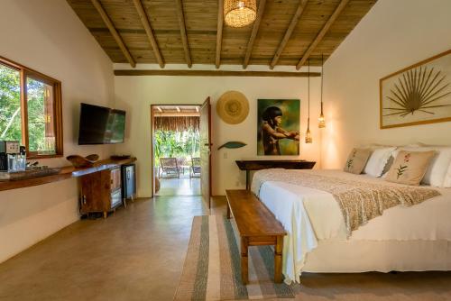 a bedroom with a bed and a table and a tv at Vila Morena Altos de Itapororoca in Trancoso