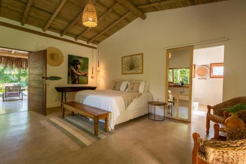 a bedroom with a bed and a table in a room at Vila Morena Altos de Itapororoca in Trancoso