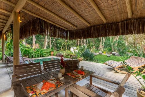 een terras met een tafel en stoelen en een zwembad bij Vila Morena Altos de Itapororoca in Trancoso