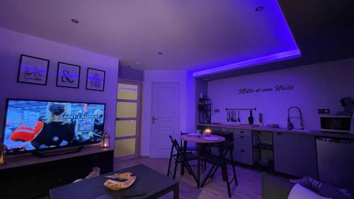 a living room with purple lighting and a tv and a kitchen at Mille et une nuit, appartement classé 3 étoiles en RDC avec exterieur et parking in Dole