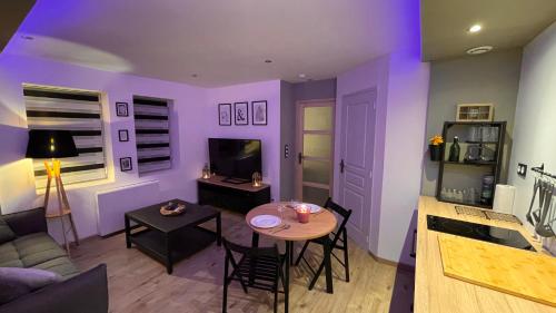 a living room with purple walls and a table and chairs at Mille et une nuit, appartement classé 3 étoiles en RDC avec exterieur et parking in Dole