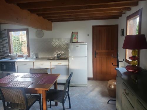 a kitchen with a table and a white refrigerator at LA PAGODE in Osmoy-Saint-Valery