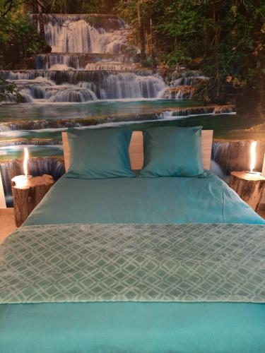 a bed in front of a painting of a waterfall at Le Pélican in Huisnes-sur-Mer
