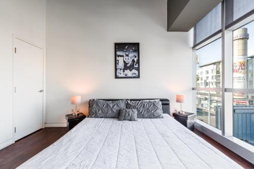 - une chambre avec un grand lit dans une pièce dotée de fenêtres dans l'établissement 1BR Furnished Apartment in Hollywood - Walk of Fame apts, à Los Angeles