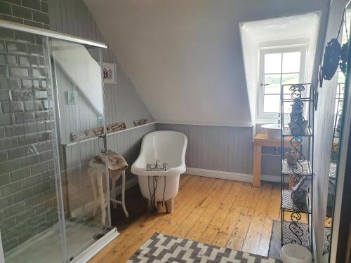 a bathroom with a shower and a white chair at Argyll Mansions Penthouse in Oban