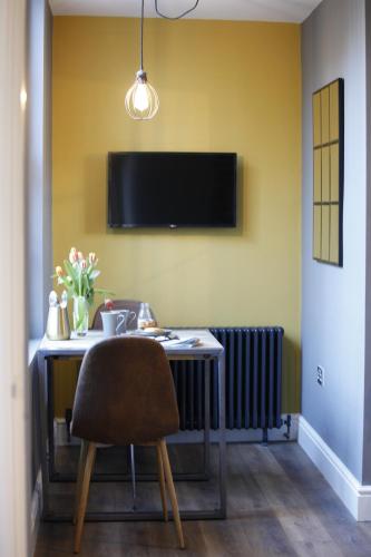 a table with a chair and a television on a wall at no 12 - Stunning Self Check-in Apartments in Worcester Centre in Worcester