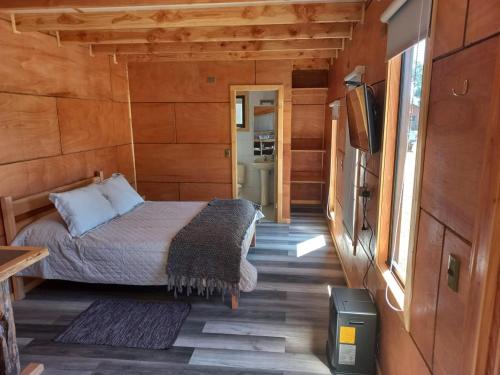 1 dormitorio con 1 cama en una casa de madera en HelChiloé Cabañas, en Piruquina