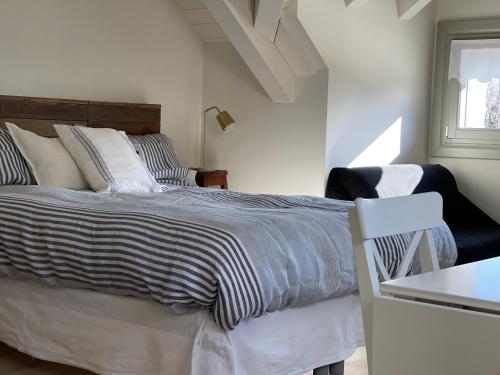 a bedroom with a bed and a chair and a window at Loft Naturalpina Dolomiti Farm in Belluno