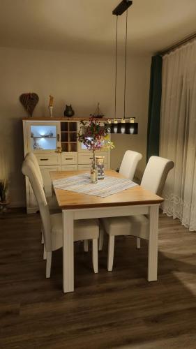 a dining room table with white chairs and a television at AnkerZeit - Wellnesswohnung in Damp in Damp