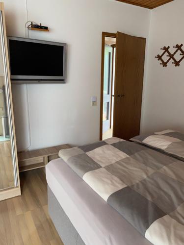 a bedroom with a bed and a flat screen tv at Gästehaus Steuer in Bruttig-Fankel