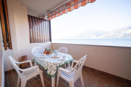 a table with white chairs and a table with a view of the ocean at Peler Beth's House in Brenzone sul Garda