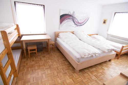 a bedroom with a bed and a desk and two windows at Familienzimmer in Neumarkt in der Oberpfalz