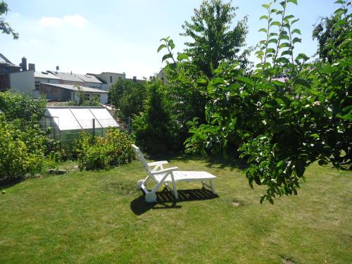 a white bench sitting in the grass in a yard at Hotel Wilhelmshof in Ribnitz-Damgarten