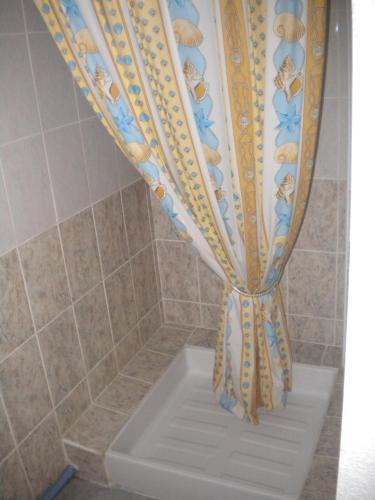 a shower curtain in a bathroom with a tub at Hôtel L'Acropole in Nissan-lez-Enserune