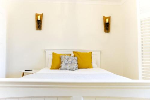 a white bedroom with a bed with yellow pillows at Stunning & unique apt in Culross in Culross