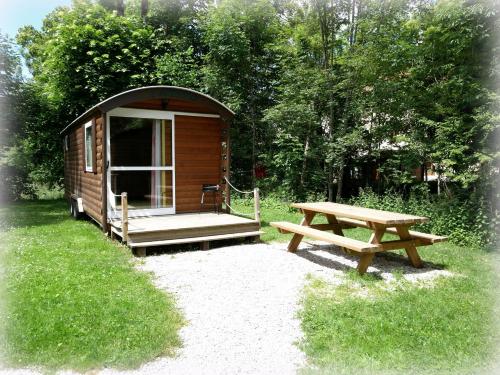 a wooden cabin with a picnic table and a bench at Auberge de la Rivière in Foncine-le-Haut