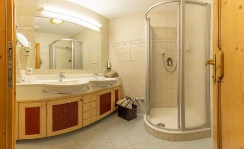 a bathroom with a shower and a sink and a tub at Hotel St. Georg in Mayrhofen