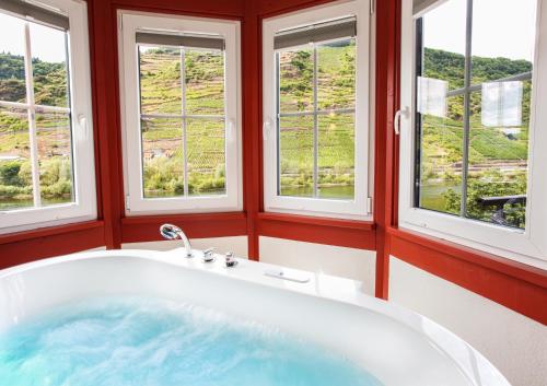 a bath tub in a room with windows at Hotel Filla Andre in Ernst